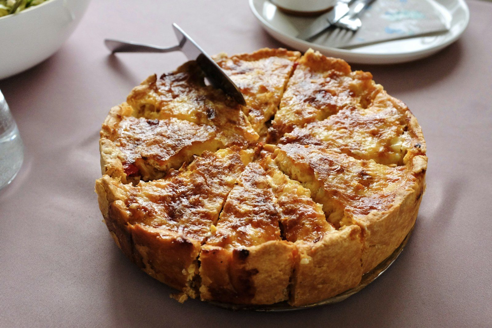 złota tarta quiche z widocznym nadzieniem, jeden kawałek wycięty