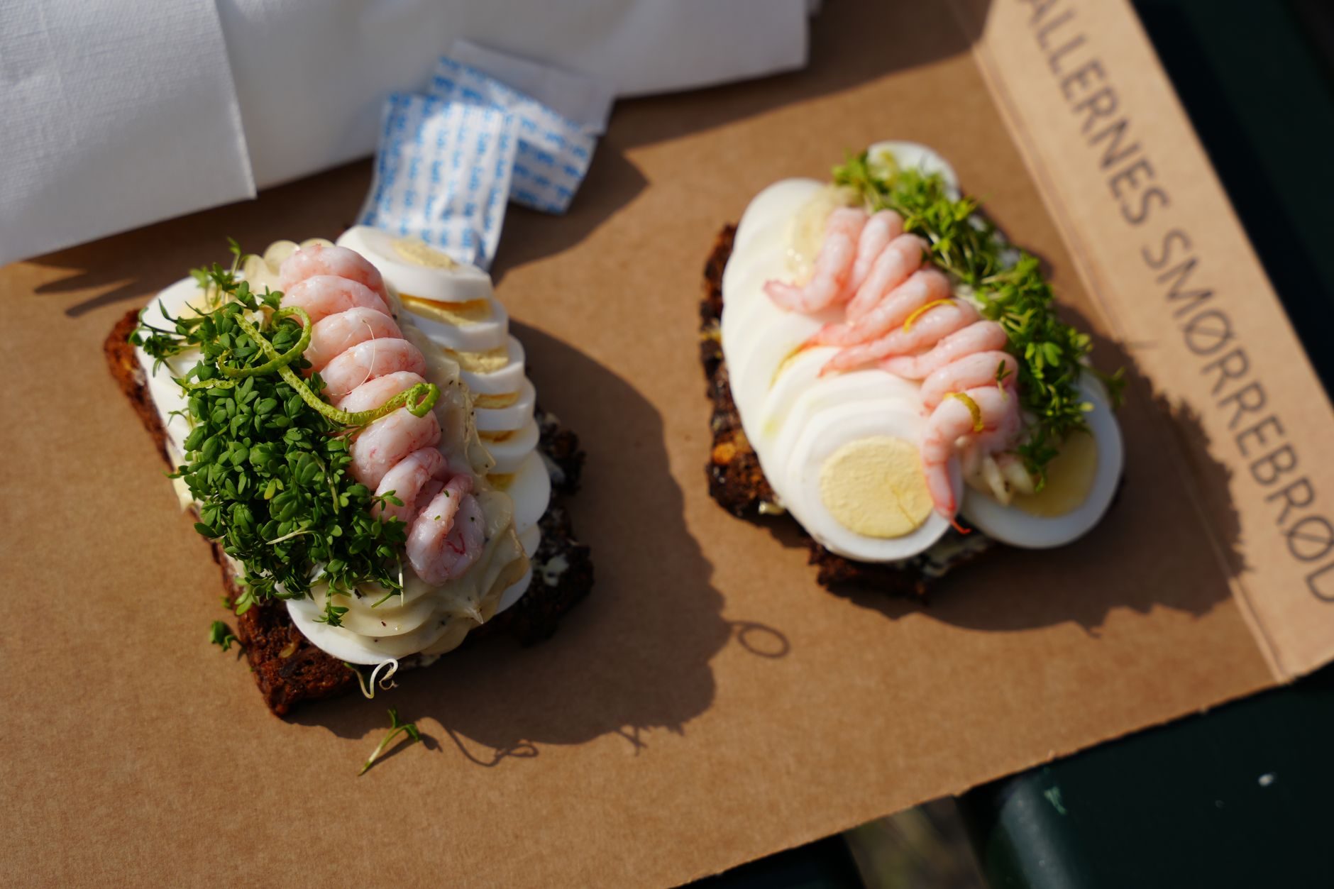 trzy kanapki smørrebrød ze śledziem, krewetkami i rostbefem