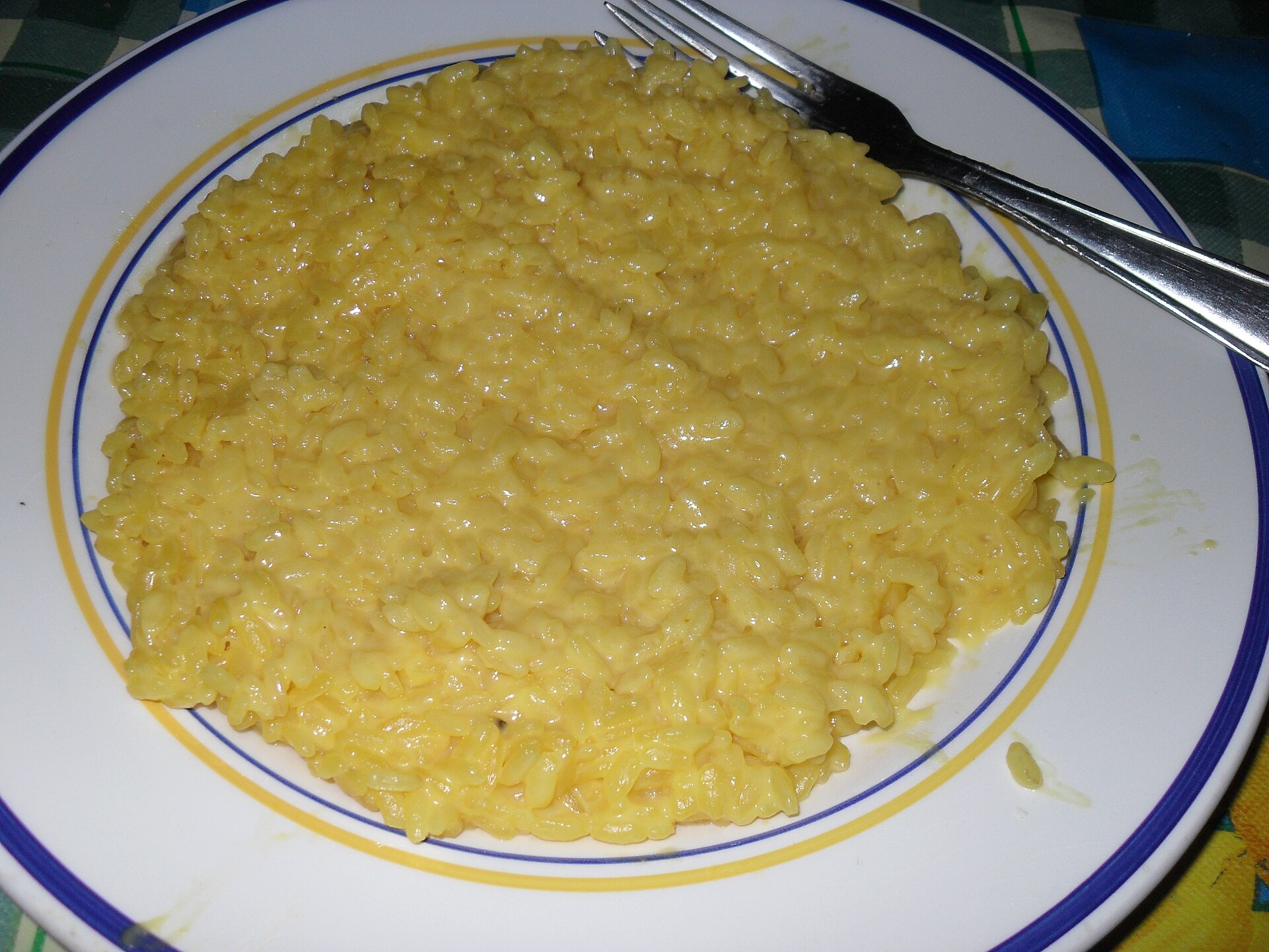 złote kremowe risotto rozlewające się płasko na białym talerzu