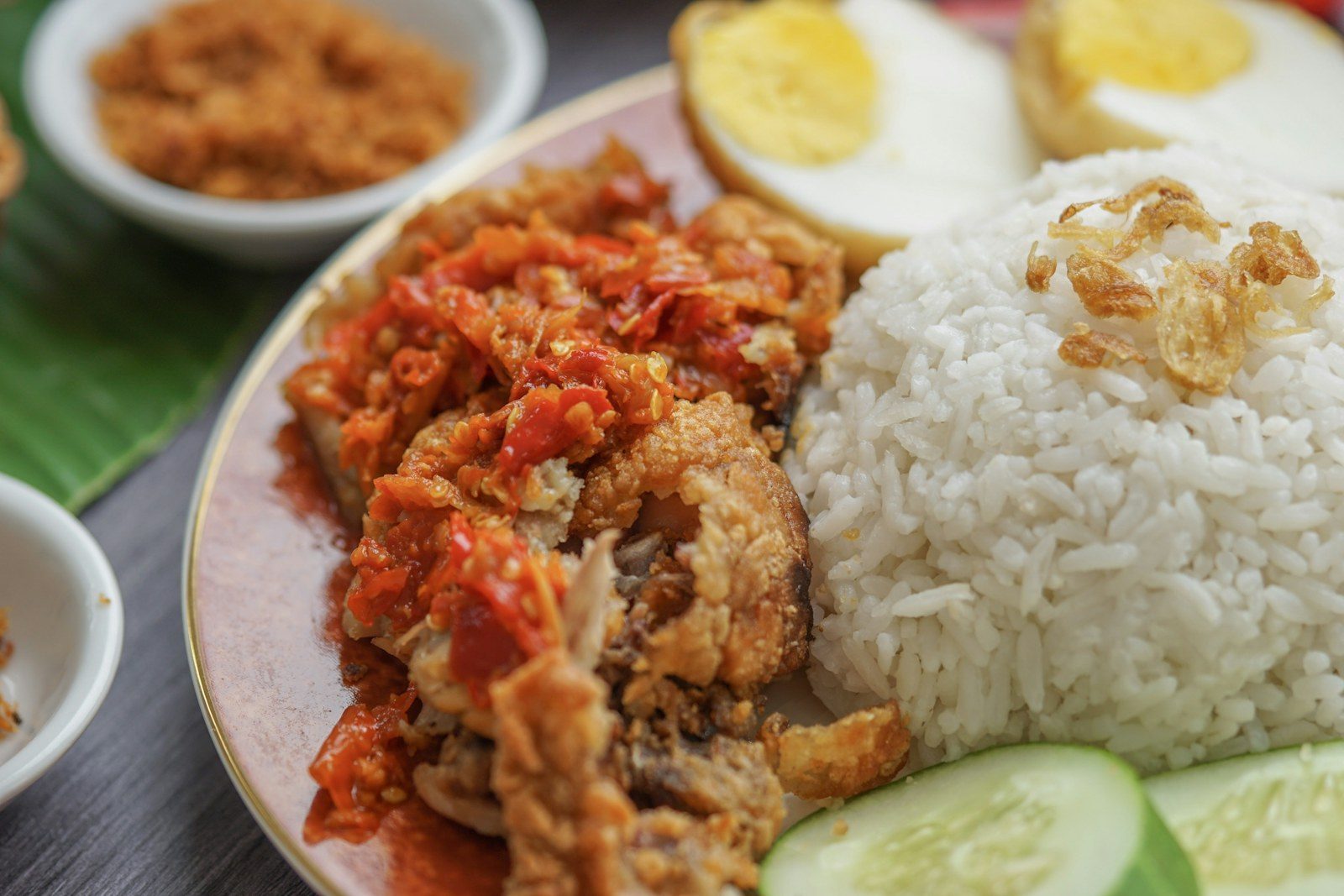 porcja kurczaka hainanese z lśniącą skórką obok kopczyka ryżu i sosu chili